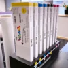 Nazdar 2000 Series digital solvent ink cartridges for Roland ECO-SOL MAX inkject printers are shown inserted vertically into a Roland printers ink ports, with the carts branded with APS and Nazdar corporate graphics.