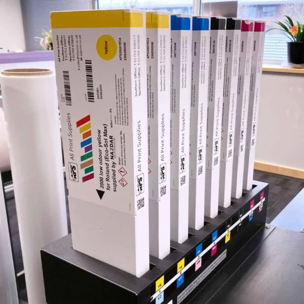 Nazdar 2000 Series digital solvent ink cartridges for Roland ECO-SOL MAX inkject printers are shown inserted vertically into a Roland printers ink ports, with the carts branded with APS and Nazdar corporate graphics.