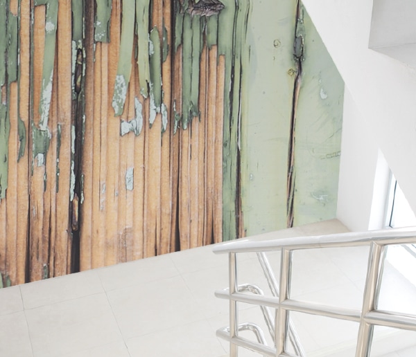 Avery Dennison MPI 8024 smooth custom printed wallpaper decorating a stairwell wall custom printed with a rough planks design in bare wood tan colours and peeling lime green paint.