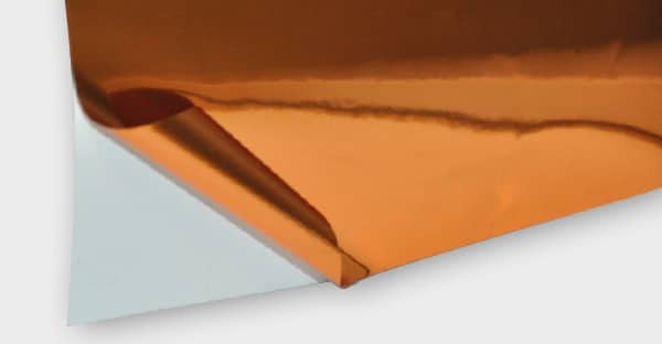 T74-P-P bright two-way copper metallised sign film showing reflections of light in the shiney bright surface. One corner of the film is folded back to reveal the release liner which clearly shows the two-way viewing nature of this film, as the adhesive side looks exactly the same as the glossy front side.