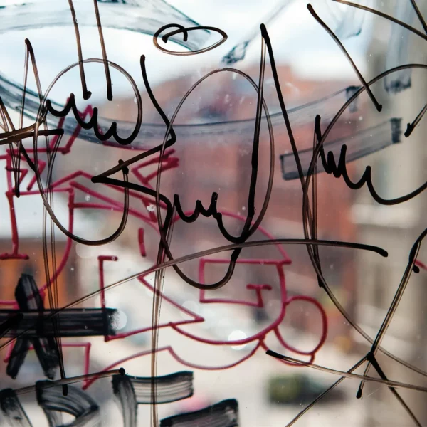 Anti-Graffiti protection laminate, AGU-30, adds protection to prints from tagging and vandalism damage. Image shows graffiti on a clear window which can be easily cleaned away with proper cleaning agents, due to the properties of this graphics protection film.