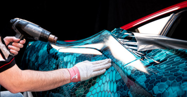 Applying Avery Dennison MPI 1105 EA RS printed wrap vinyl over the smooth curved contours of a sports car with a stylich, printed blue honeycomb graphic design.