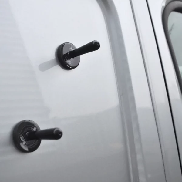 Two vehicle wrapping magnets are randomly attached on the side of a van prior to offering up a large wrap vinyl to hold it in position before removing the liner and fixing the adhesive side to the substrate.