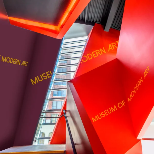Avery Dennison 700 Performance Film series of sign vinyls used to decorate different aspects of a staircase within a modern art museum with cut-vinyl self-adhesive lettering as well as use of solid complimentary coloured vinyls to cover the wall and ceiling areas in this abstract shaped, architecturally interestingly stairwell area.