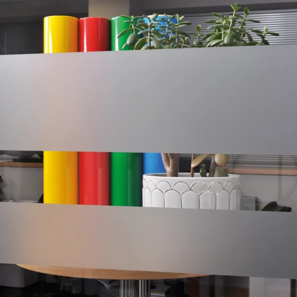 Avery Crystal etch glass effect self-adhesive decorative vinyl is applied to an internal office window in 2 large strips to show how the obscurity/privacy levels of this window film only allows light and vague colours to be visible through the areas that the film has been applied onto.