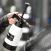 PPF Slip Solution 1L spray bottle held in one hand, liberally spraying fluid onto a windscreen.