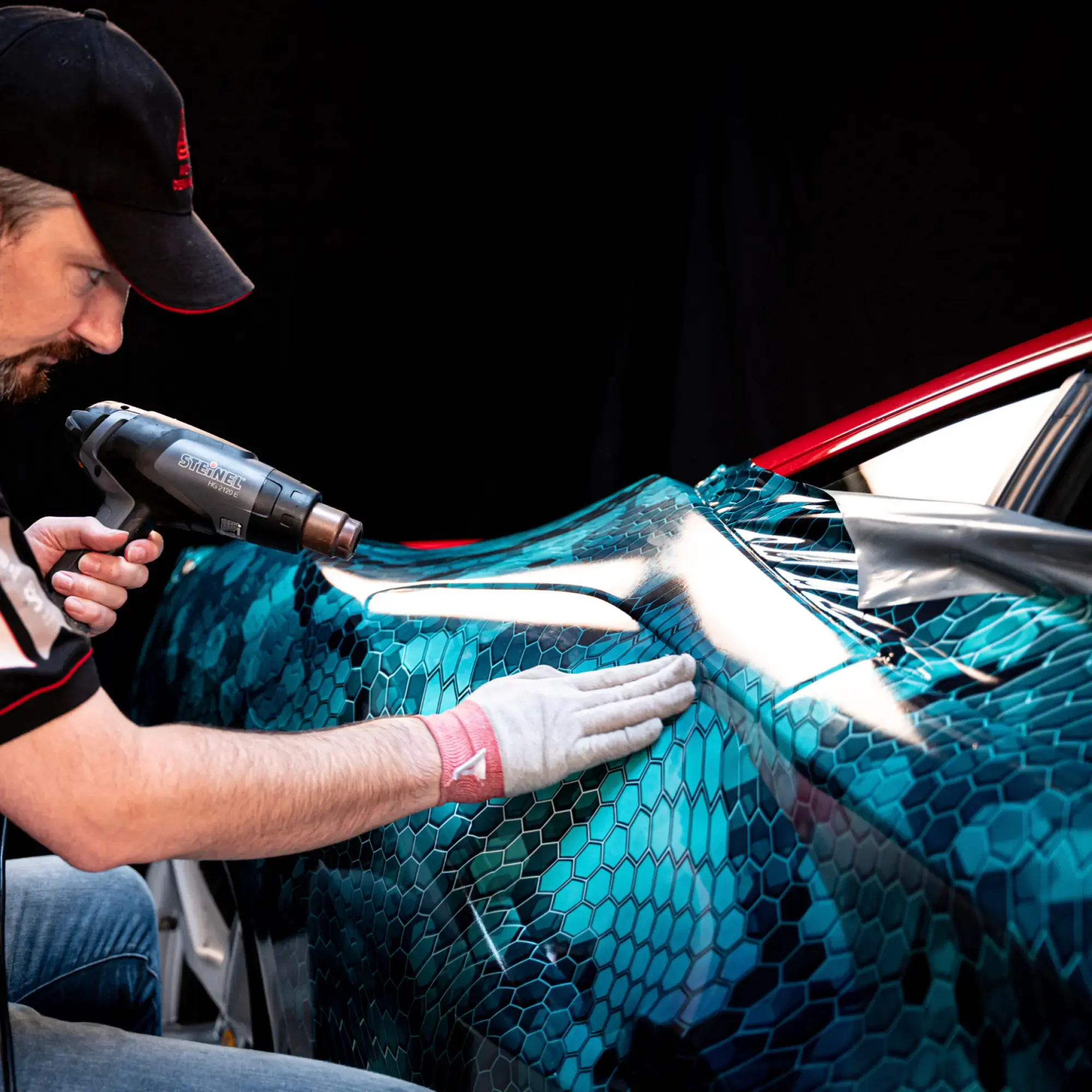 Heating vehicle wrap graphics into the contours of a sleek sports car with the printed wrapped graphic laminated with Avery Dennison DOL 6560 High Gloss PU film.