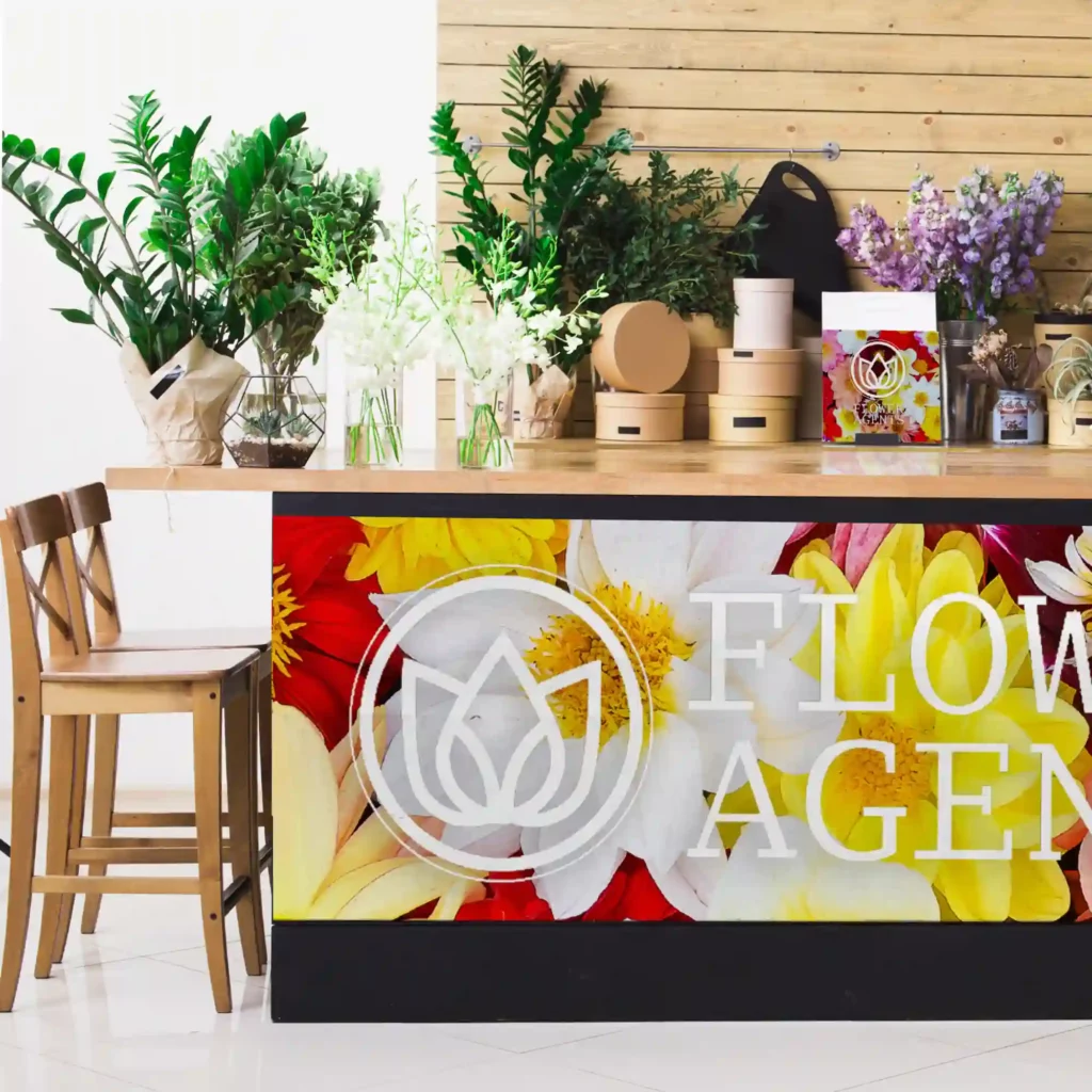 Avery Dennison MPI 2000 Standard Opacity Series of print vinyls for general self-adheive promotional prints and advertising signage with a colourful print applied below the counter top in a florists shop with brand graphics of brightly coloured flowers and a company logo in white on top of the flower imagery.