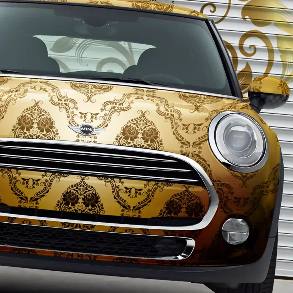 Avery Dennison MPI 1104 EA cast print vehicle wrap vinyl, printed with an elegant golden coloured paisley wallpaper design, offset against the black trim of this mini cooper car.