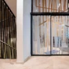 Avery Dusted self-adhesive window film with a cut-vinyl abstract shape design applied to various large office partition windows with the cutout shapes of the film matching the decorative interior of the buildings ironwork that surrounds the staircase bannisters.