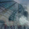 Avery SF 8 i Bomb Blast window protection film has been applied to protect this fully glazed modern city building, and imposed over the top is an image of glass with a typical spiderweb patterned scar, typical of shatterproofing properties provided by this self-adhesive safety laminate, holding the glazing together after blast impact or vandalism.