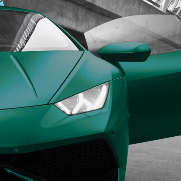 Silky-looking Pearlescent colours from the Avery Dennison Supreme Wrapping Films range of self-adhesive vinyls add a touch of class and a unique Pearl Dark Green coloured finish to the sleek contours of a sports car, with the image focussing on the opened door, wing mirror, bonnet, headlight and radiator grill, viewed from the front.