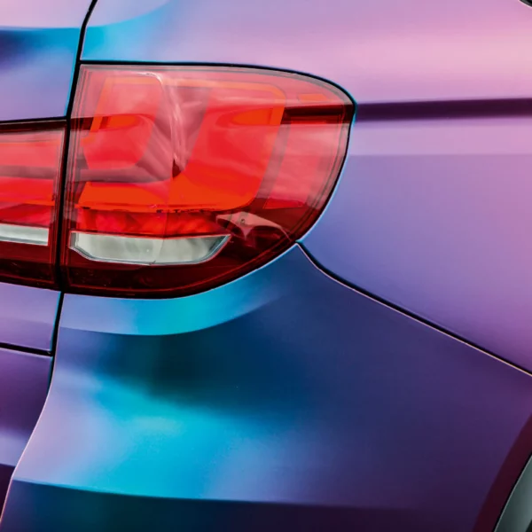Roaring Thunder Blue/Red colour-changing vinyl wrap film is applied to the intricate shapes of this modern road car with a close-up focus on the panel edges around the rear lights, showing off how the colour changes with the angle of the reflected light from the contoured surface of the vehicle.