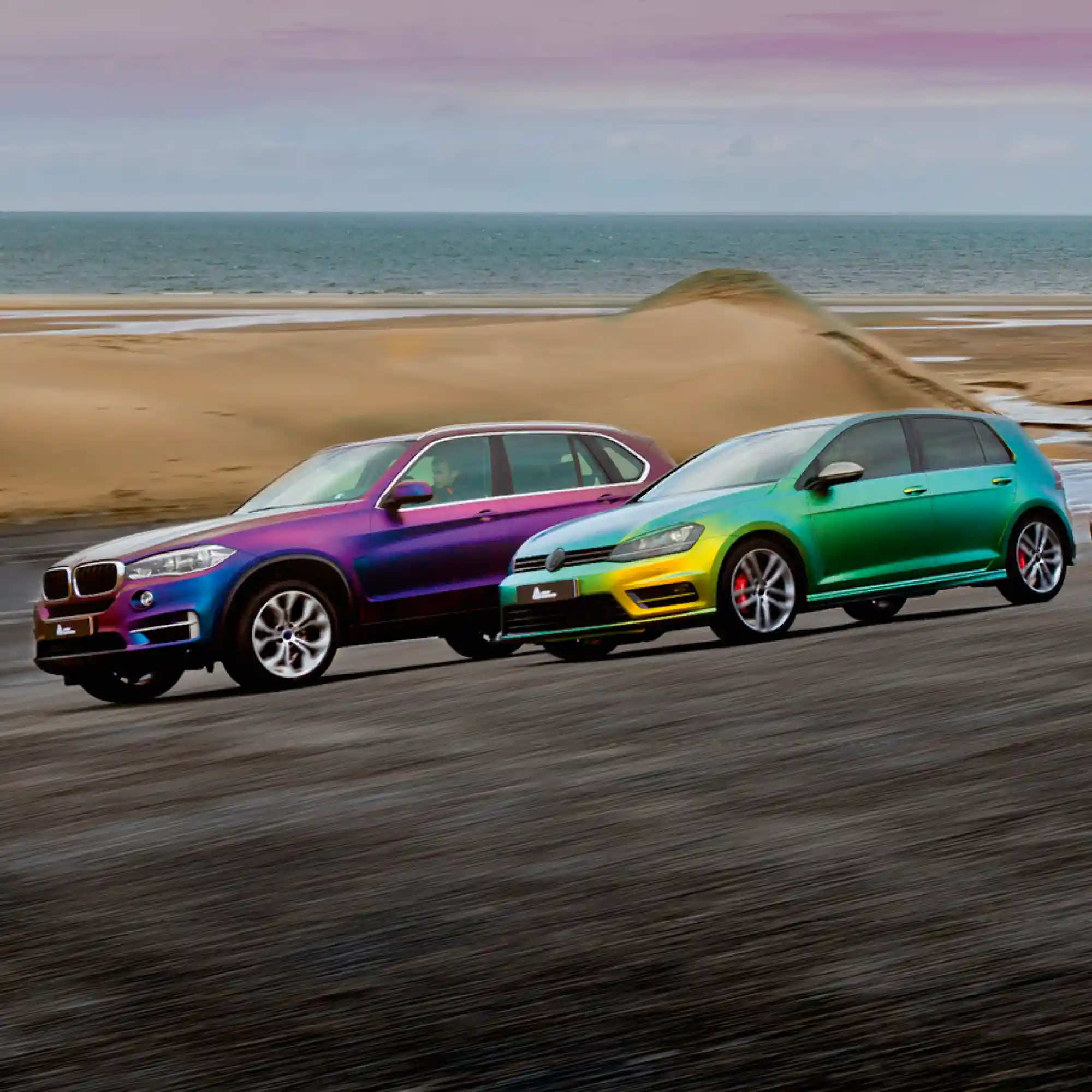 Avery Dennison's Supreme Wrap Colorflow vinyls offer satin, iridescent vinyl wrap colours and this photo shows two of the colour change films wrapped onto a couple of well known car models that are driving on a beech with an atmospheric purple sky in the background and the eye-catching Rushing Riptide Cyan/Purple and Fresh Spring Gold/Silver colour-change vinyl colours used on each vechile are really 'popping' out from their surroundings.