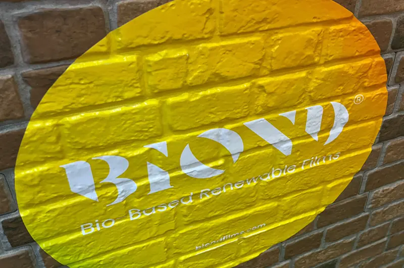 BIOND plotter cut printed round yellow branded graphic applied over the textured surface of a rough exterior brick wall surface.