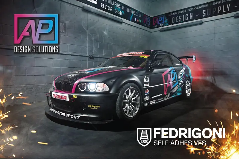 A stunning motorsport graphic vinyl wrap produced by AP Design SOlutions using Fedrigoni C50 print vinyl and C30 matt laminate, the BMW car is situated at a slight angle and looks heroic in the installation studio as fireworks pop at the bottom corners of the image in celebration of a superb example of vinyl wrapping and branding design!