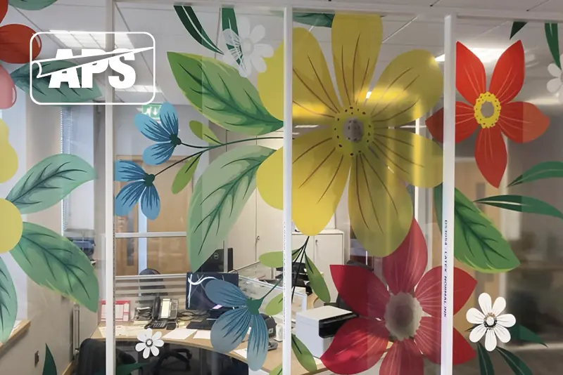 Various window films digitally printed in a wide-format floral design and applied to the interior glass office partition windows at the APS sales office in Slough. Large, bright primary coloured petals spread out across the full width of the room with a translucent effect as light comes through the inks.