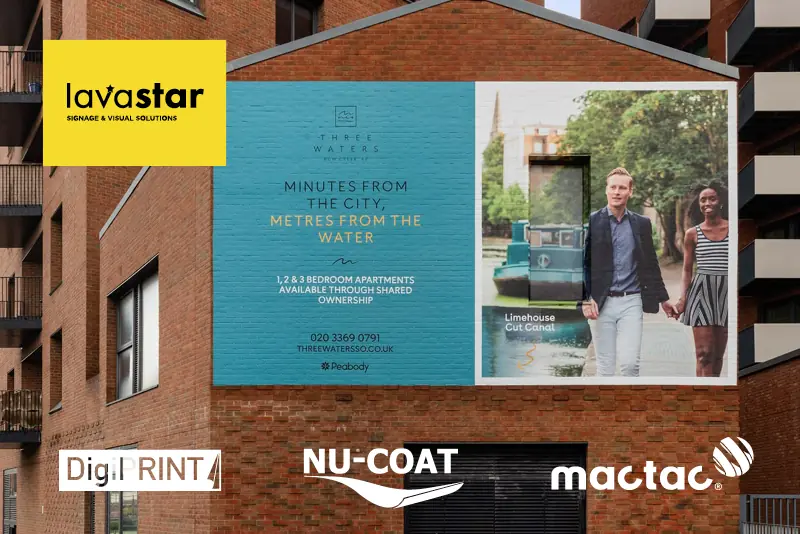 A large scale sign hoarding graphic applied directly onto a brick surface using Mactac self-adhesive wall wrap vinyl WW100, applied to cover almost the entire side of a building featuring printed advertising graphics for housing developments and on such a large scale that the promotional signage cannot be visually missed!