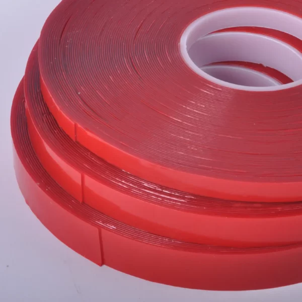 Clear double-sided sign tape, UHB-C-10F Ultra High Bond tape in close-up to show the 3 x different widths of tape on their red liner with the thickness of the 1mm UHB adhesive tape clearly visible.
