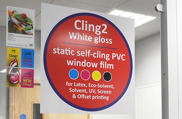 Cling2 static-cling print vinyl, S11-Z White film printed with white text over a large bright red circle sign graphic and the white film has been applied onto an internal window for the purpose of self-promotion for the static cling vinyl it has been printed onto.