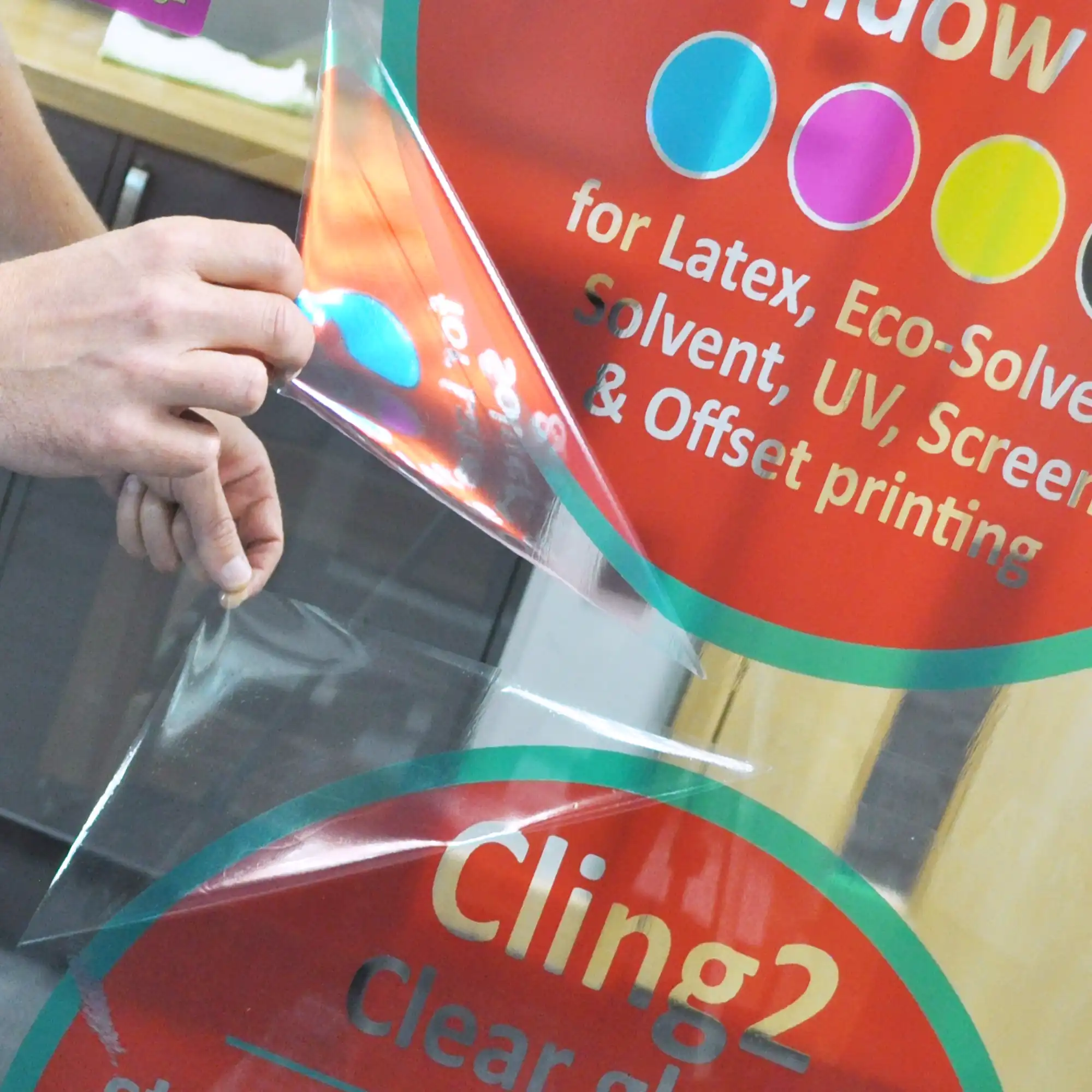 Cling2 S21-Z clear staic cling window print vinyl signs have been applied onto opposite sides of an internal glass partition wall and are being peeled back at the corners to demonstrate how these films are designed to be repostionable, and can be easily moved and re-applied onto smooth clean surfaces multiple times over.