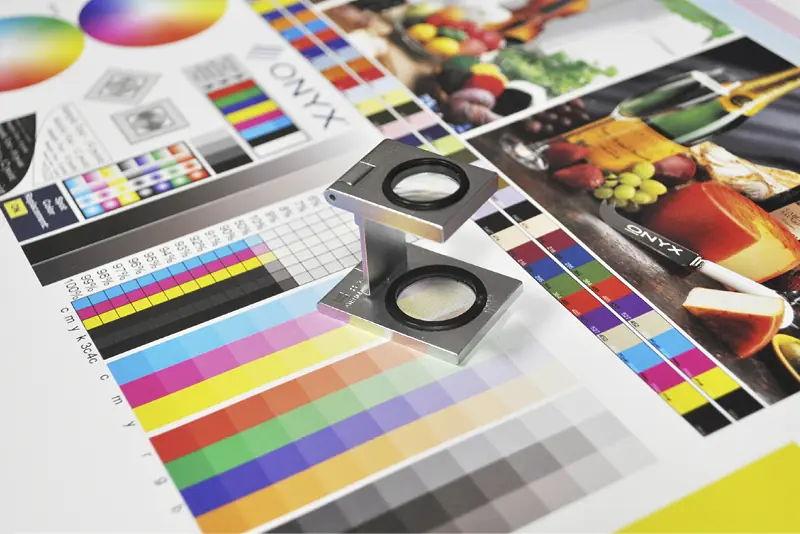 A linen tester in sharp focus as quality is tested and inspected on a colour profile print out.