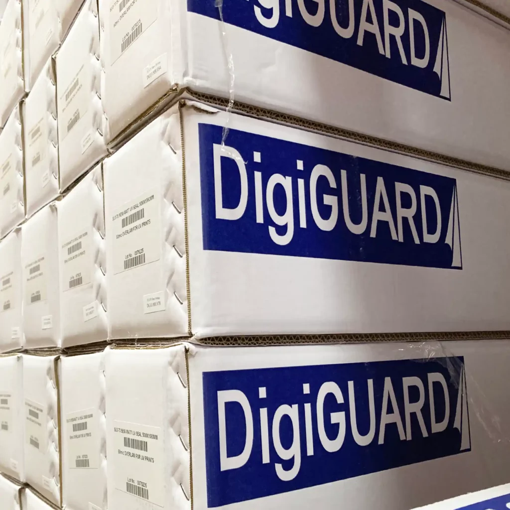 DigiGUARD GU4 gloss UV ink print laminate, ideal for mid-term self-adhesive signage is pictured in ots branded packaging boxes stacked neatly within APS' Slough warehouse shelving.