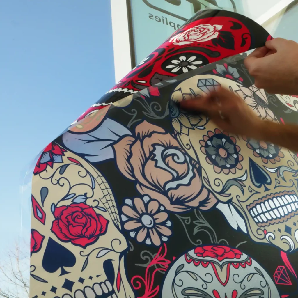 A printed window sign on ultra-clear ClingSil CSC130 film being applied with a squeegee. The high-transparency film showcases vivid, sharp graphics while allowing for a seamless, professional installation on glass surfaces.