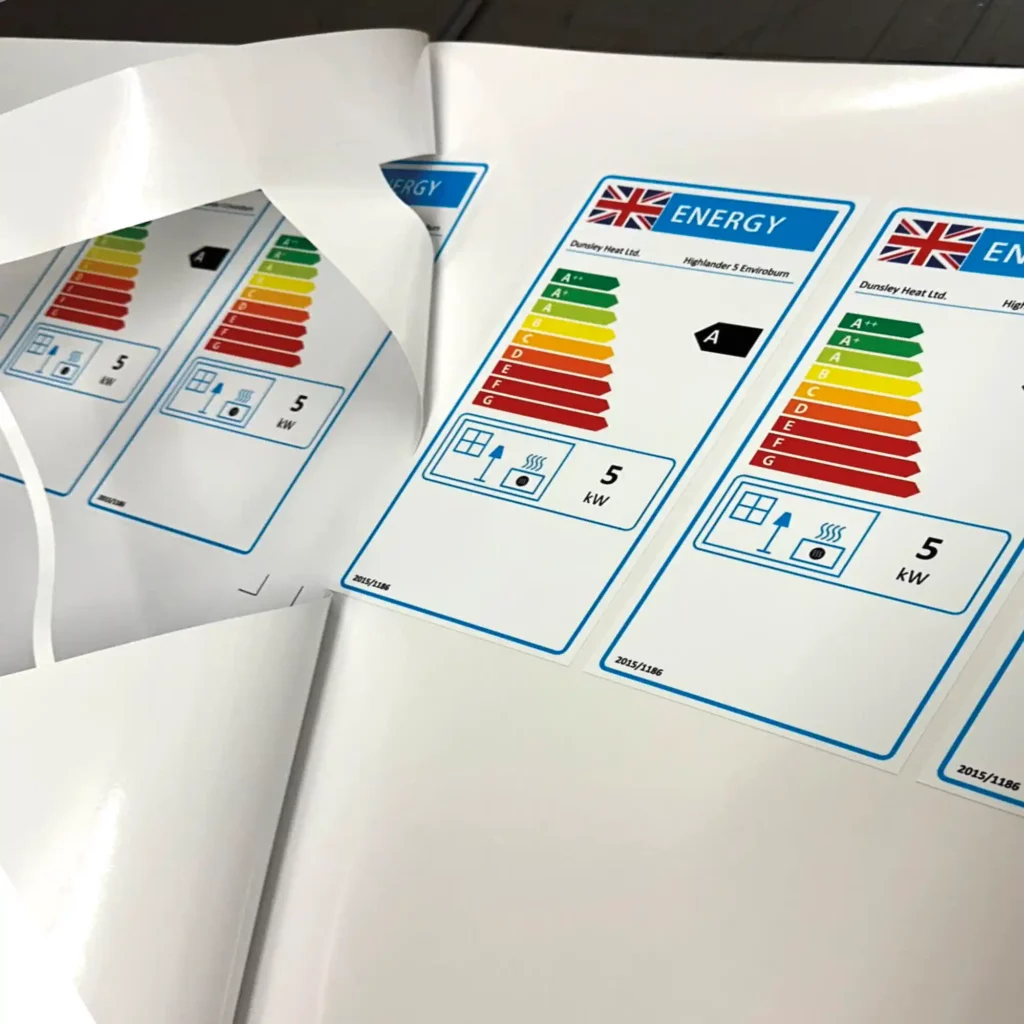 DigiPRINT monomeric series of thick print vinyls are ideal self-adhesive print films for producing cut labels and stickers. DS3007 gloss white film is shown printed with energy labels, often found on electronics packaging, and the printed roll is laid on a table shown in the process of being weeded out / the excess unwanted film that surrounds the printed graphic being peeled back and removed.