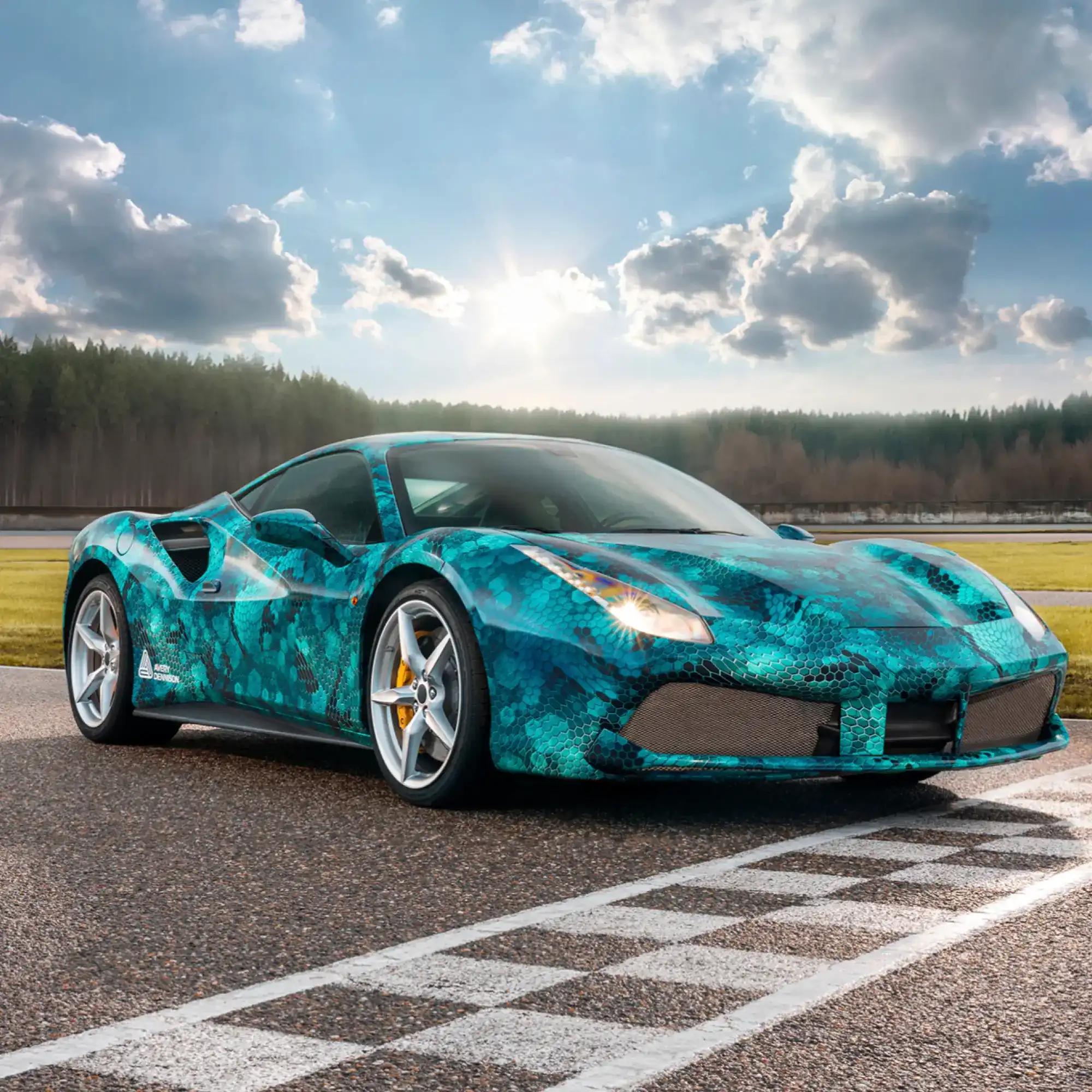 DOL 1460 Z Gloss car wrapping laminate protecting the printed self-adhesive film that features a geometric shaped, blue snakeskin style design that has been applied to a highly contoured sportscar which sits on a race track start line.