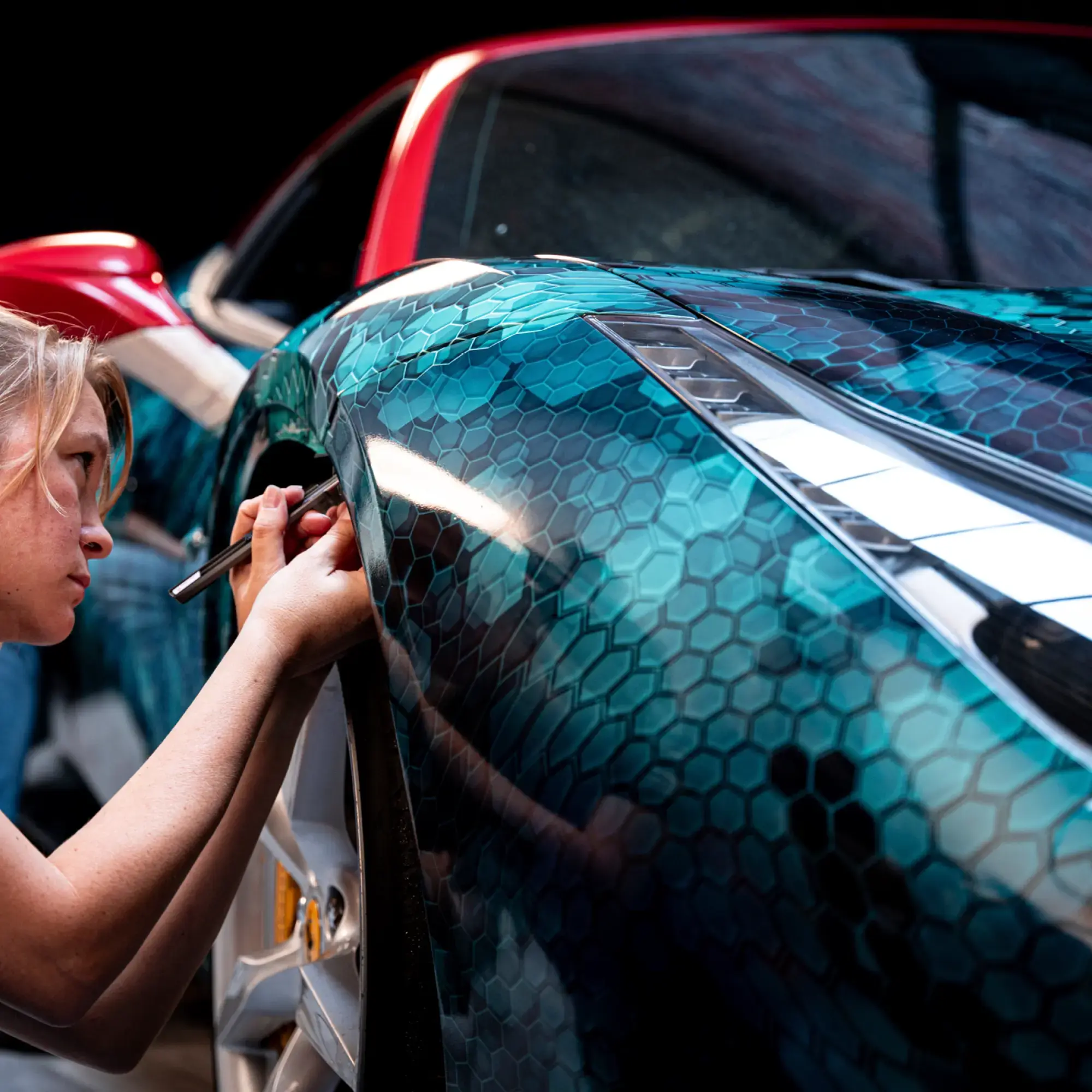 Applying the final touches to a vehicle wrap graphic, conforming the print and Avery Dennison DOL 6560 High Gloss PU wrapping laminate film into the wheelarch contours.