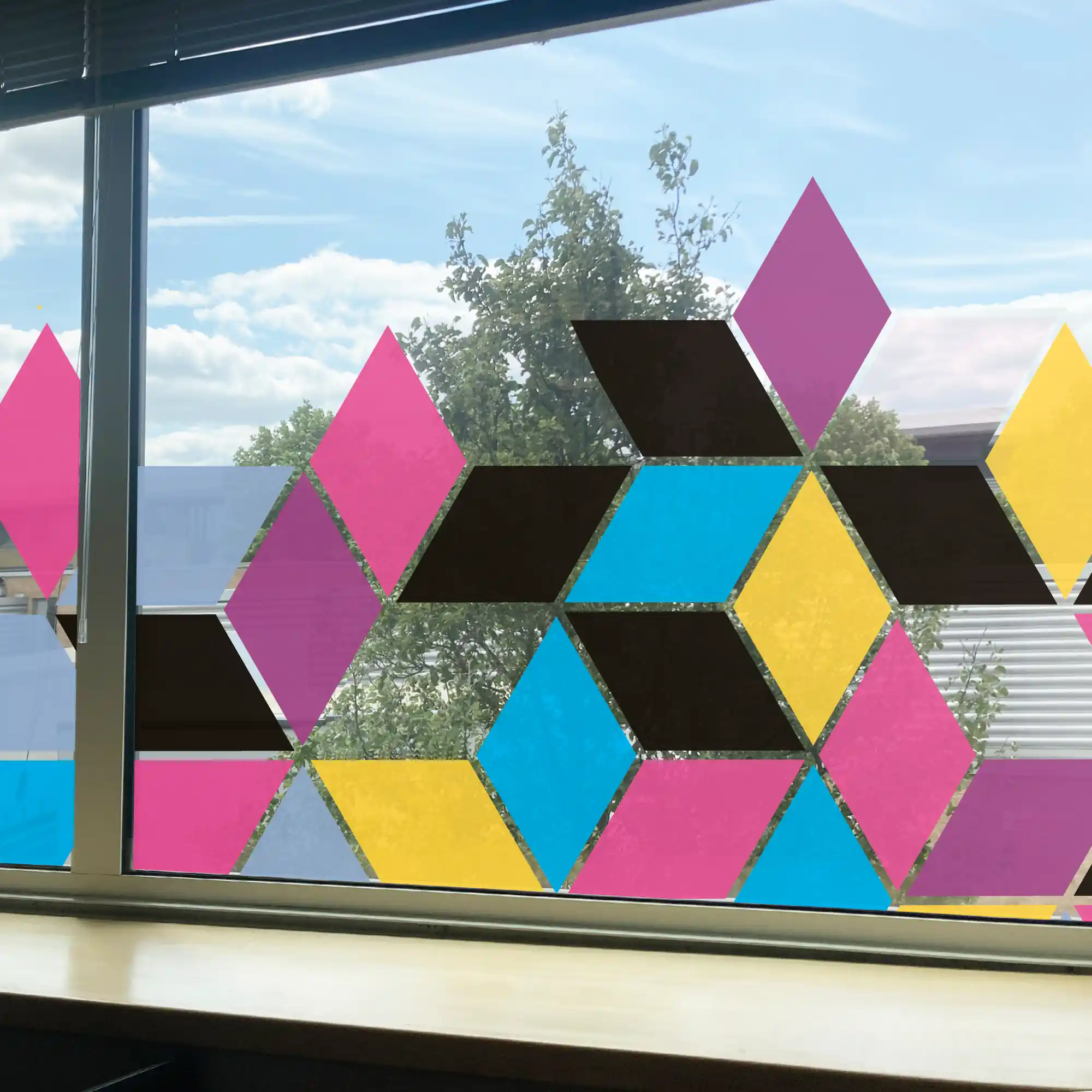 This photo of DigiPRINT DS1001 Crystal Clear self-adhesive print film showcases the ultimate clarity of a latex printed graphic that has been applied to the inside of an office window. The vibrant printed abstract geometric box design features see-through gaps within the image, allowing the outside view of trees and clouds to be clearly seen in the external background.