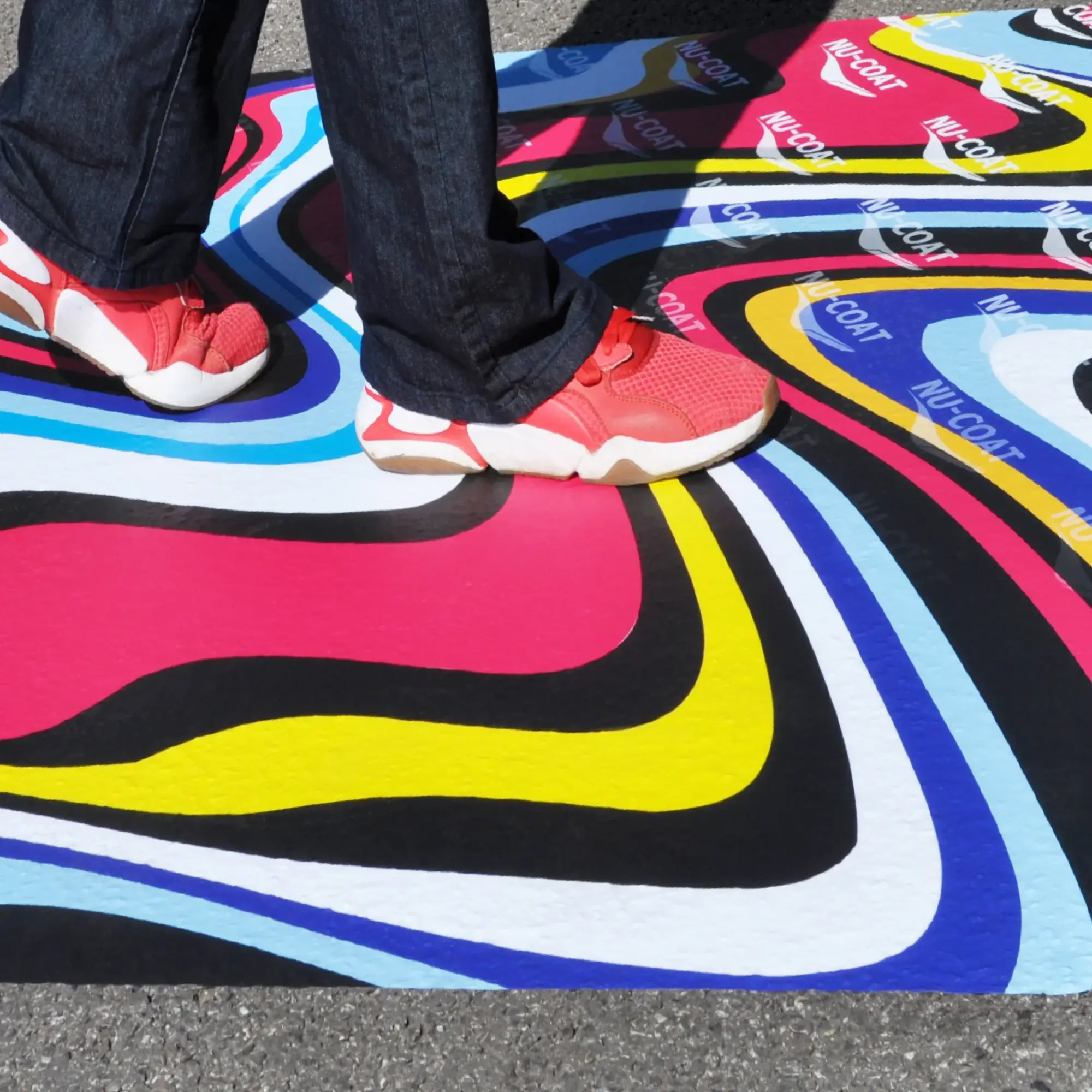 NU-COAT's M77-P slip-rated floor print lamination film has been applied to rough external tarmac and is being walked over by pedestrian traffic.