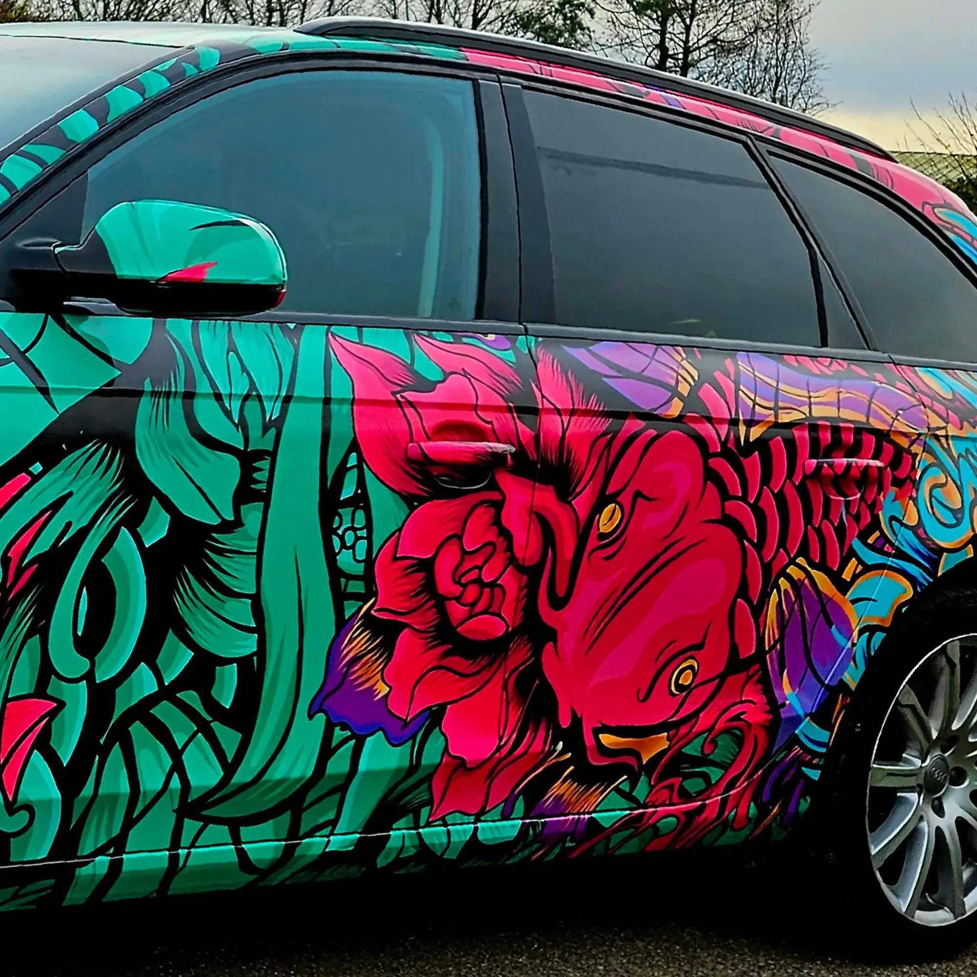 Fedrigoni C50 Ultimate vehicle wrapping print film fully wrapped onto this Audi car in a brightly printed fish and fauna red, purple and green with black outlines design, showing close-up on the side details of the cars contours and the vinyl conforming into door handles and recesses.