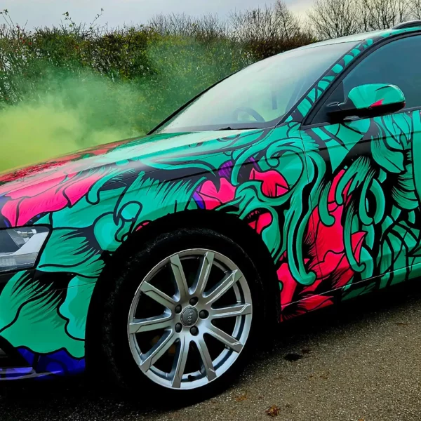Fedrigoni C50 Ultimate vehicle wrapping print film fully wrapped onto this Audi car in a brightly printed fish and fauna red, purple and green with black outlines design, showing close-up on the front detail of the car contours, around wheel trims, headlights and wing mirror.