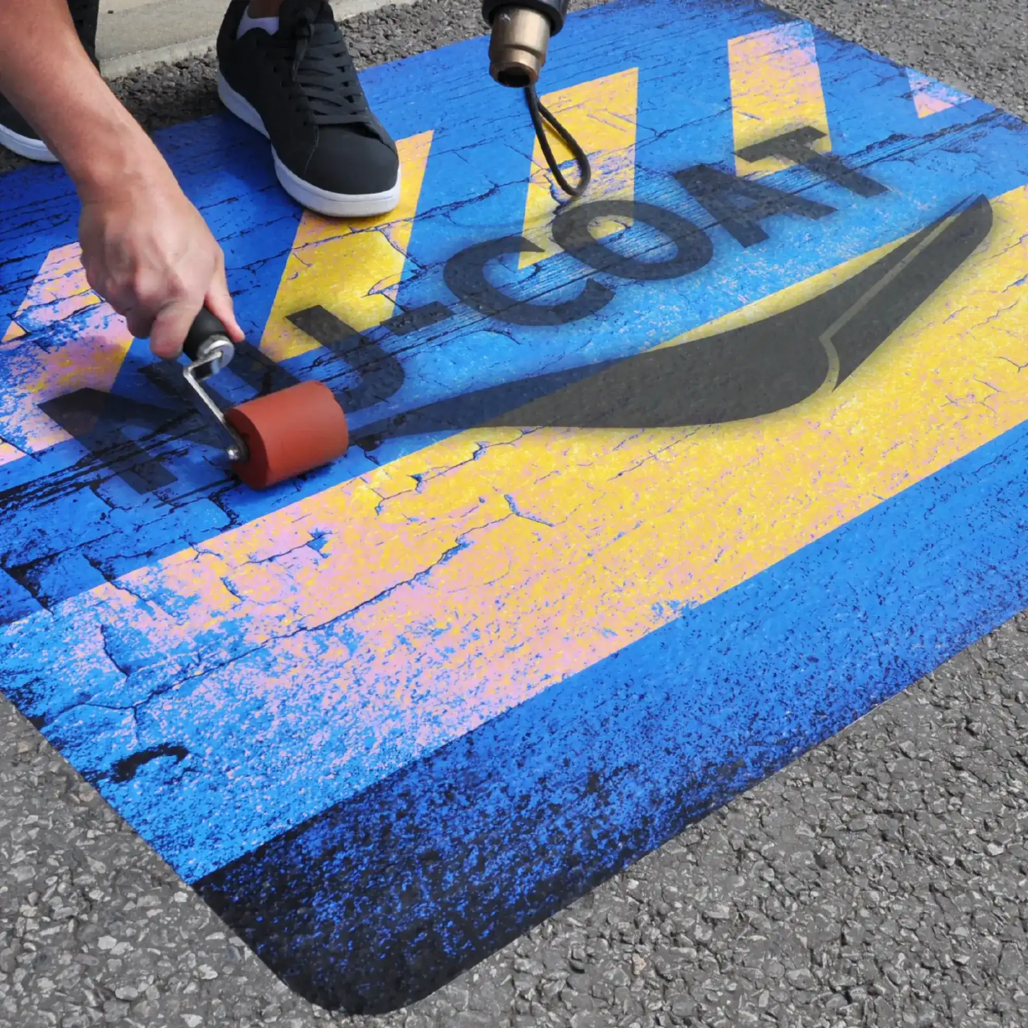 FlooR11 slip rated laminate for internal & external floor applications. with it's textured film is applied onto an external transitional area that can occasionally be wet with a NU-COAT branded logo graphic onto a tarmac surface.