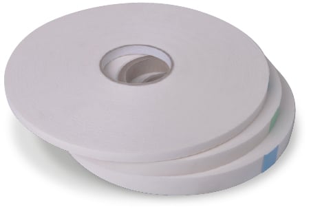 1mm thick PE foam double-sided tape in 3 reels in widths of 12mm, 19mm and 25mm stacked horizontally, one on top of the other, with the ends taped to keep the reels firmly in circlular shape on each individual reel to stop the foam tape from unravelling.