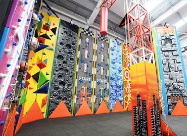 Floortex FV8-85 floor laminate is shown used to add slip-resistance and protection on a colourfully printed set of climbing wall graphics. The photo shows a wide view of all the different surfaces for climbers.