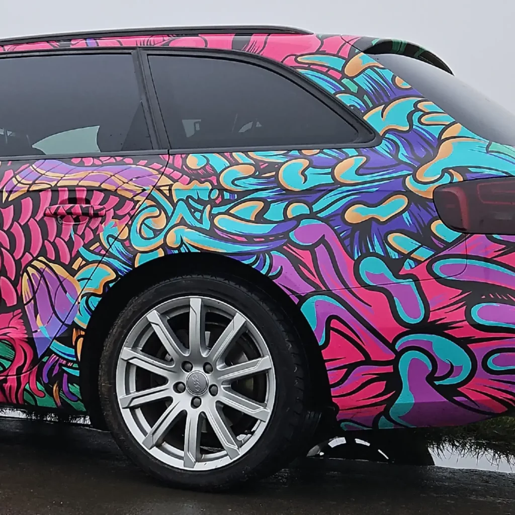 Fedrigoni C30 gloss vehicle wrap laminate on the C50 printed film, both fully wrapped onto this Audi car of a brightly printed fish and fauna red, purple and green with black outlines design, showing close-up on the rear side detail of the cars contours, around wheel trim, rear light and door handles.