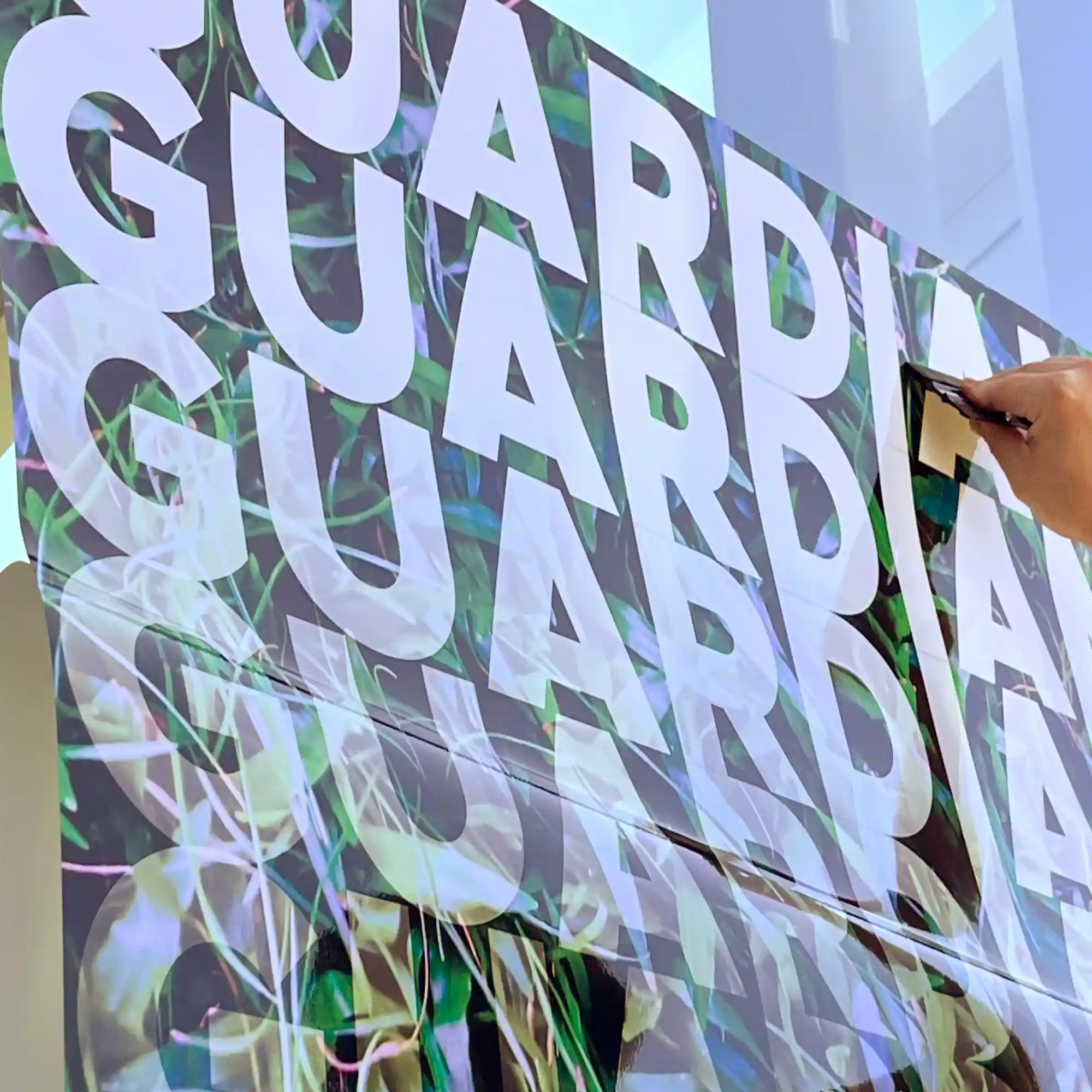 GUARDIAN Lam Matt PVC-free laminating film for covering digital printing inks has been laminated to a print films with GUARDIAN text and grass imagery and is being applied to an outside window for a short-term promotional sign.