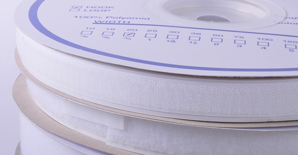 Hook and Loop tapes wound in individual reels, in white packaging stacked one on top of the other.