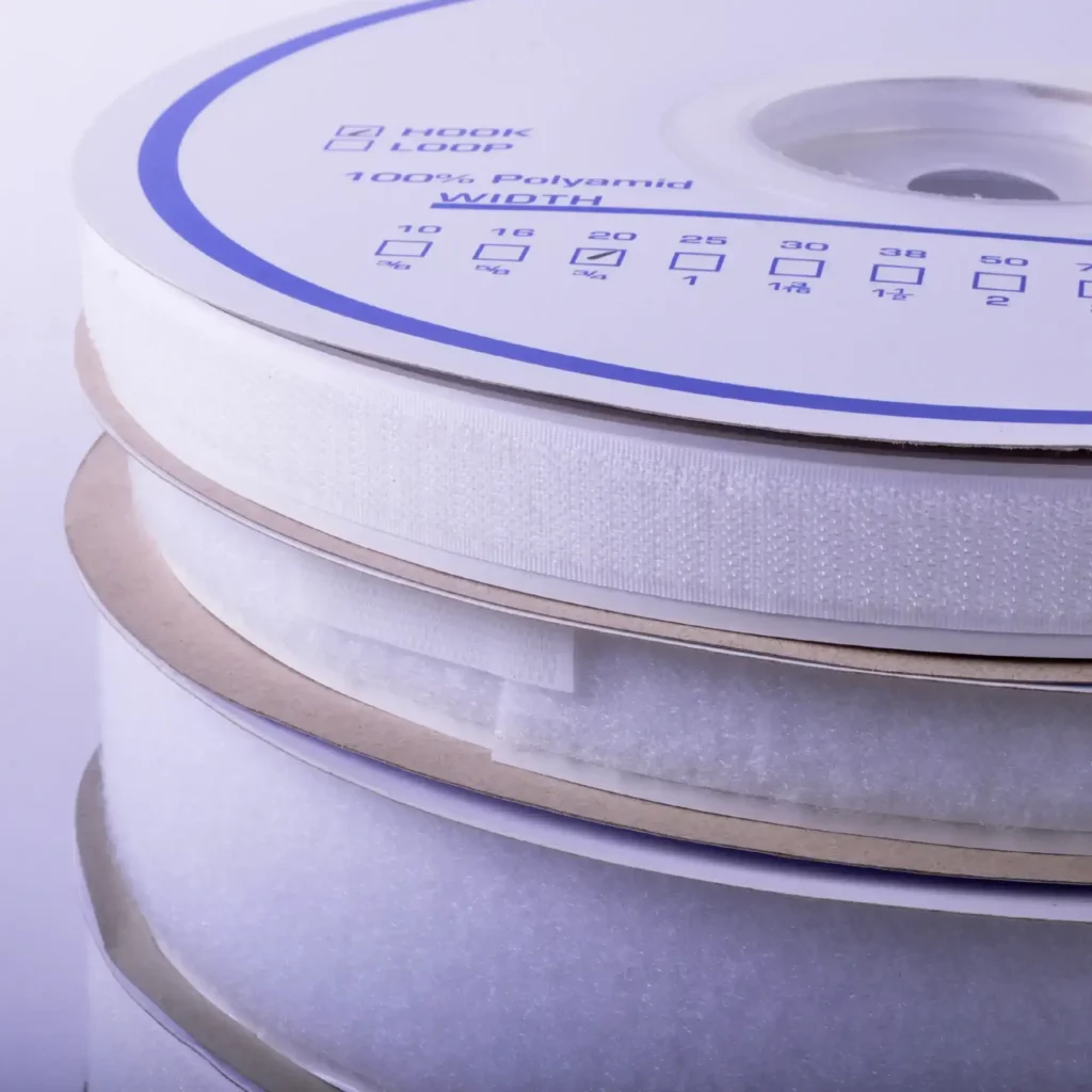 A closer look at the Hook and Loop tapes wound into their own individual reels in white printed wheel packaging and stacked one on top of the other. 20mm and 50mm width reels are shown with the narrower widths of tape on top.