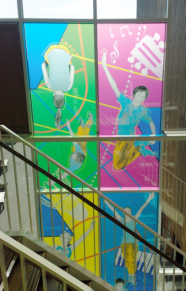 Mactac JT 9700 WT-BFT Frosted etch window film applied to school stairwell windows with a brightly coloured graphic of music symbols and kids bouncing and jumping.