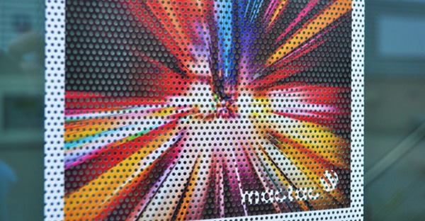 Mactac JT 7300 WG-PB 30 perforated one-way vision window film close-up photo of a light explosion printed image in a spectrum of reds, oranges, yellow and blues. You can clearly see the hole to vinyl ratio of the perforations in the film which allow the light through the film while still showing a great view of the colourful graphic that can only be viewed from the front, printed side.