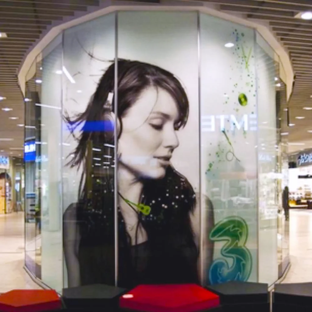 Mactac JT 9500 CG-RT clear transparent gloss removable adhesive printed graphics vinyl applied to a glass booth advertising display in a shopping precinct.
