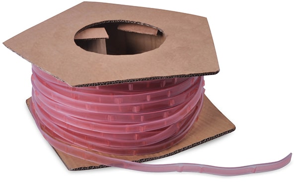 Keder PVC self-adhesive fabric hemming tape for frames is pictured in its roll of brown cardboard drum packaging with the pinky coloured adhesive protective lining clearly seen facing outwards from the roll packaging.