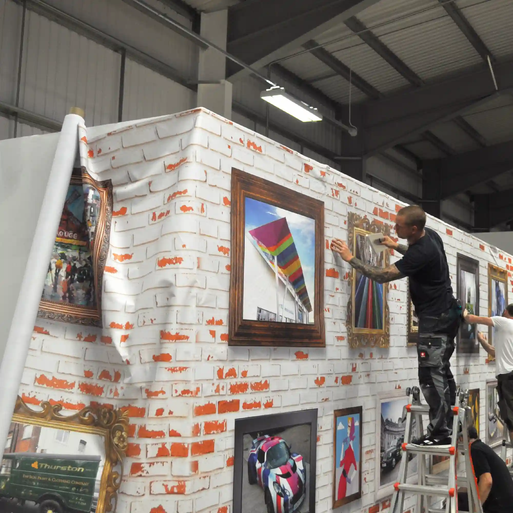 Krea Royal Majestic 1025-11 ultra-wide format display print fabric printed with a custom design of white painted bricks with different styled art frame images for the decoration of a corporate meeting area wall graphic.