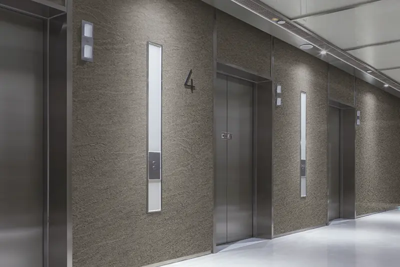 Lift and wall facade refurbishment of an office block lobby area, using complimentary warm stone patterned finishes to breath new life into a previously tired and worn large room area..