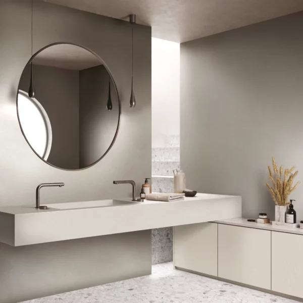 LX Hausys painted wood grain textured interior films with a solid colour finish from the 'SM' range of self-adhesive vinyls decorate the walls, counter tops and cupboard doors of this sleek looking, light and spacious washroom with feature furnshing such as a very large circular mirror and pipe taps with delicate hanging ceiling lighting.