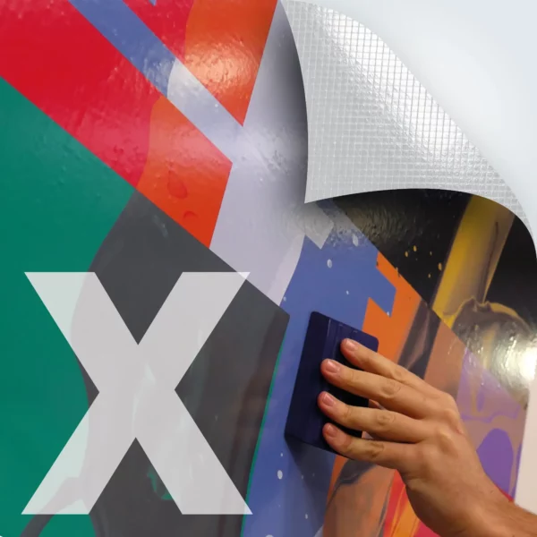 M12-P-X gloss white monomeric print vinyl with airXit air-release self-adhesive allows for faster, bubble-free application and is showne here printed with a colourful abstract design that is being squeegeed into place onto a flat surface. The top right corner of the picture includes a superimposed graphic with a folded down corner and cross-hatched lines that depict the embossed air release liner characteristics of this graphics film.
